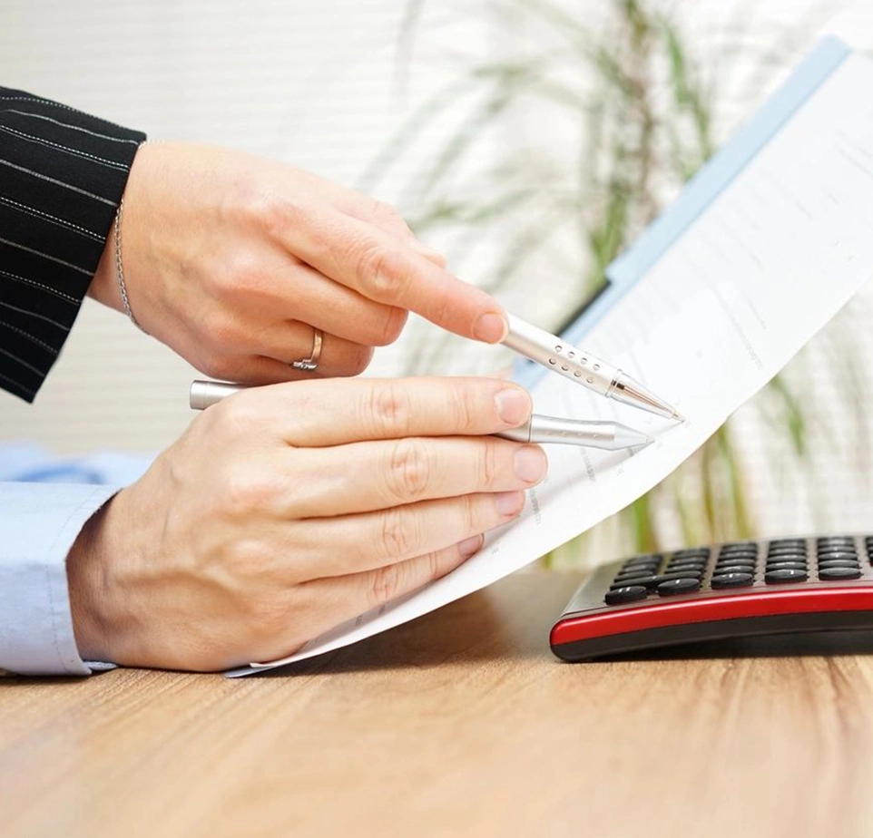 A person is writing on paper with a pen and a keyboard.